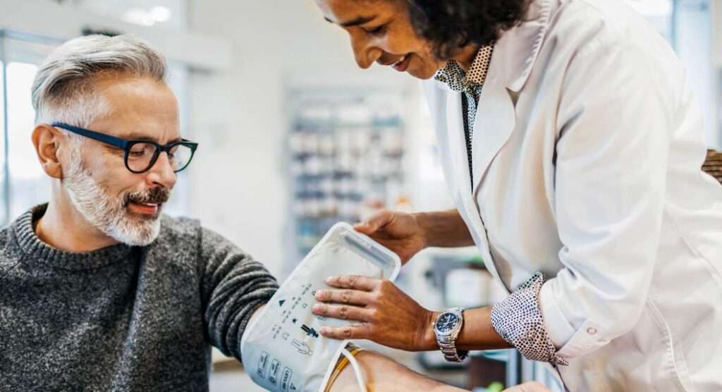 Female doctor taking a mans blood pressure