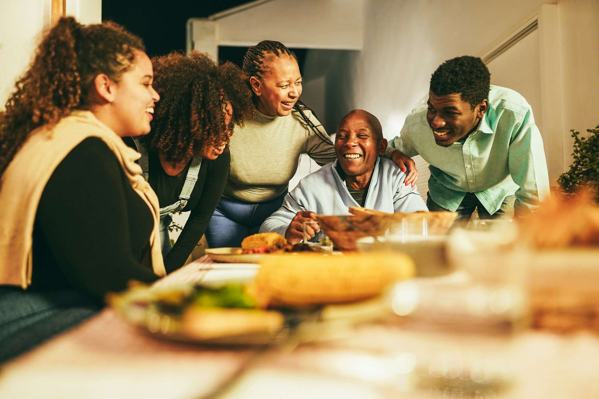 Happy african family eating dinner together at home terrace outdoor