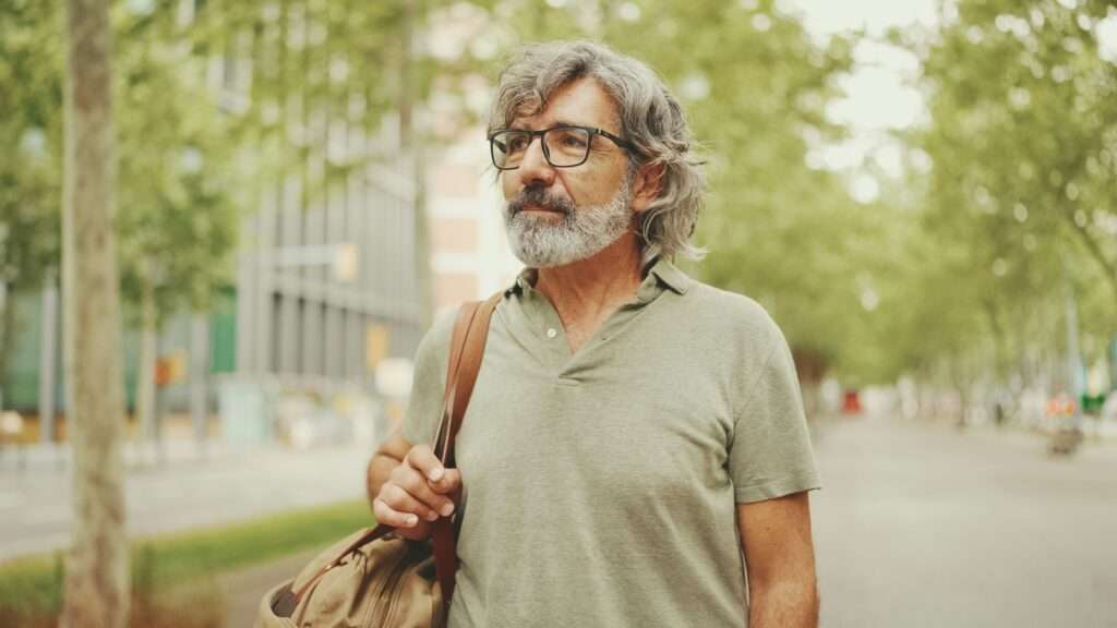 Middle-aged man with gray hair and beard walks and looks around