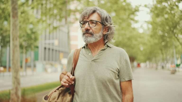 Middle-aged man with gray hair and beard walks and looks around