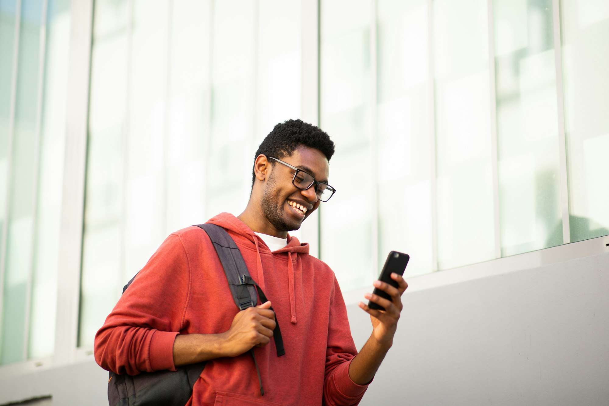 smiling young black man with glasses and mobile phone