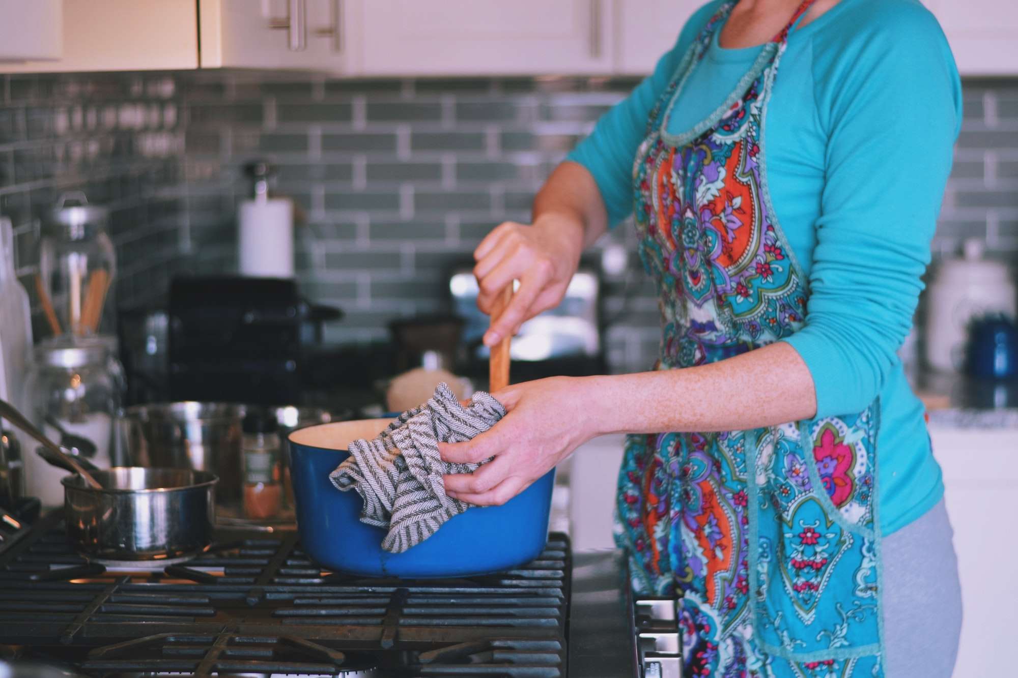 Woman is cooking dinner in a blue cast iron pot, Dutch oven, on a stove