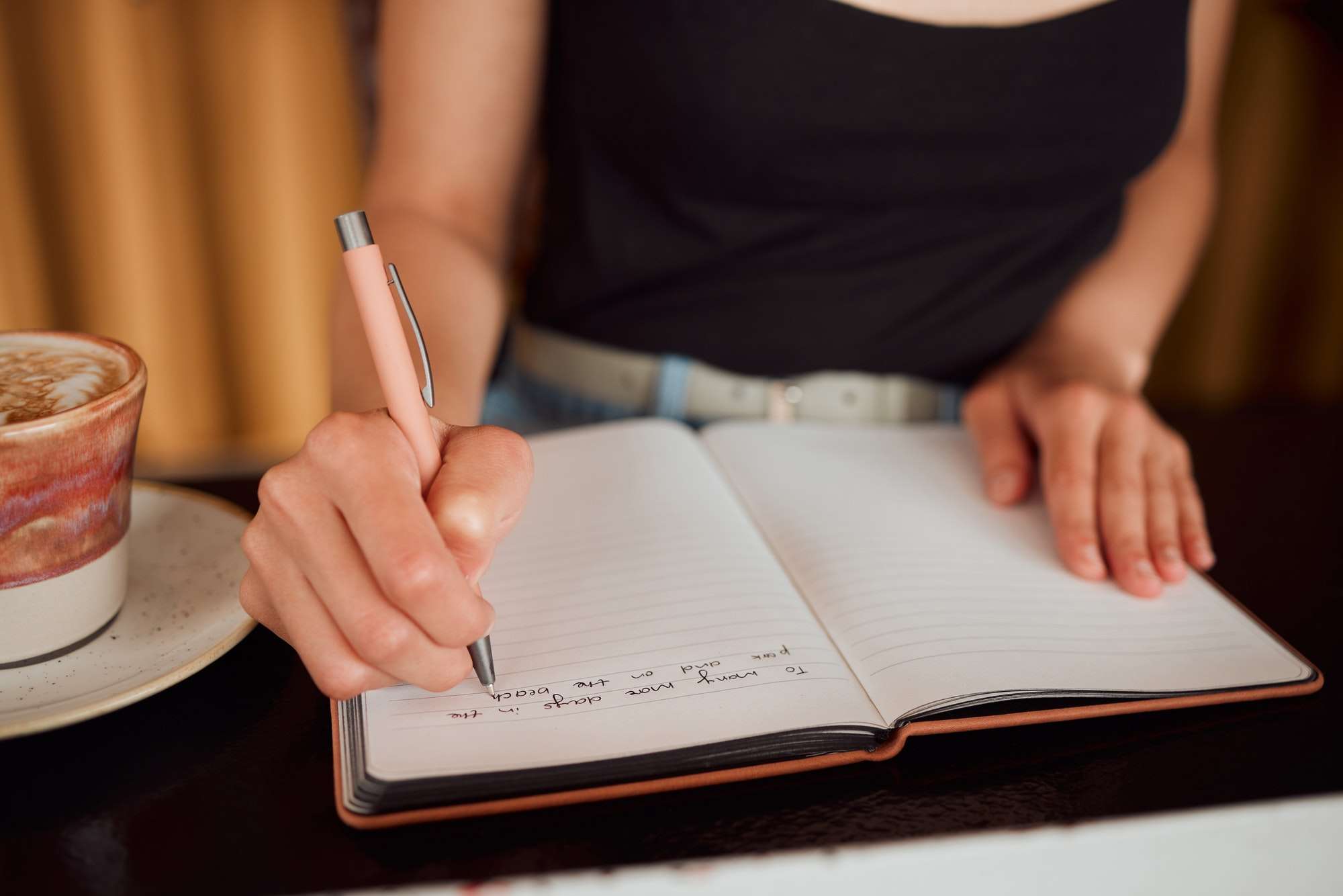 Woman writing thoughts in notebook, taking notes and doing morning journal routine at home from abo
