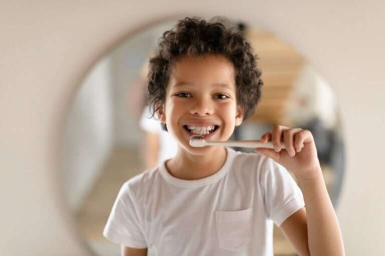 Young Boy Brushing His Teeth in Front of a Mirror